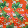 Fabric with a vibrant pattern of goldfish, lotus flowers, and green leaves on an orange background.