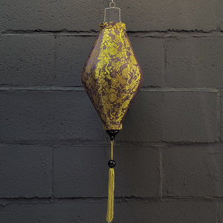 Hanging lantern with gold floral pattern against a grey brick wall