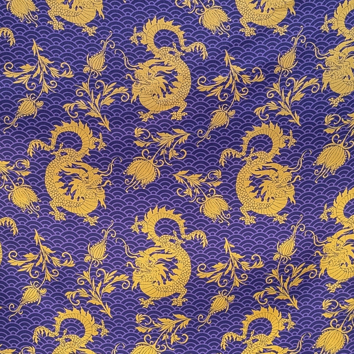 Polyester silk fabric used to create Hoi An Lanterns featuring a pattern of gold dragons and floral elements on a purple background