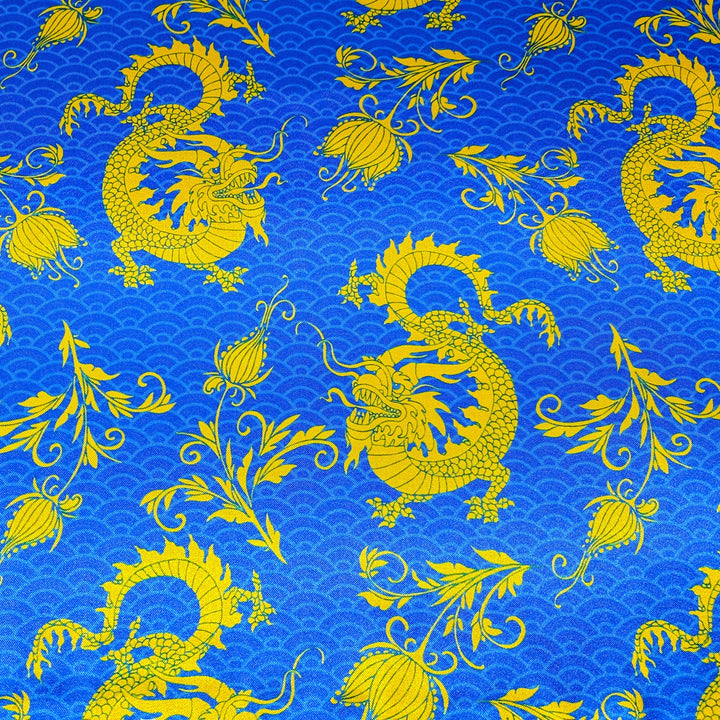 Polyester silk fabric used to create silk lanterns featuring a pattern of golden yellow dragons and flowers on a blue background with sea swirls.