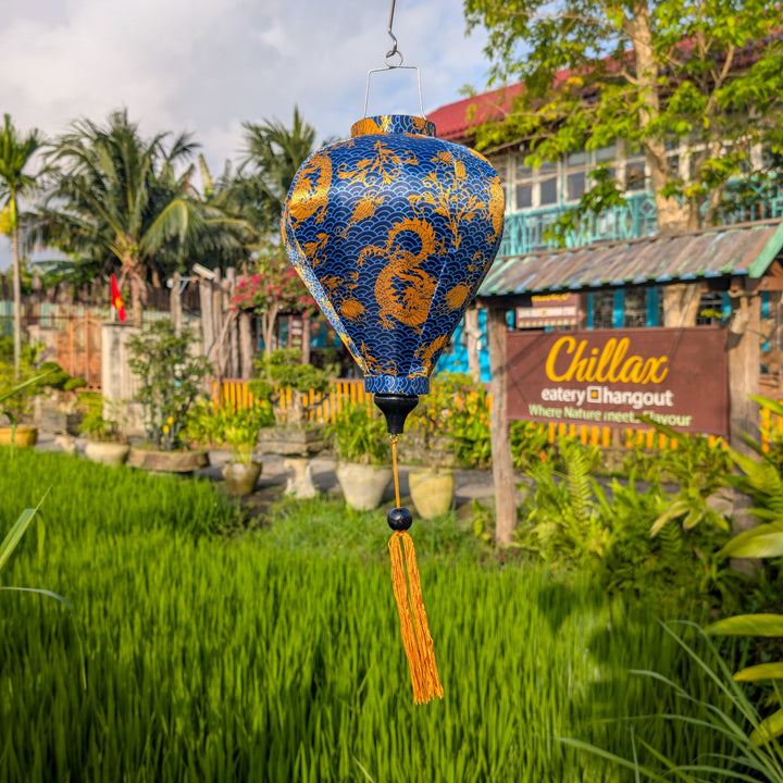 Blue and gold dragons lantern hanging in a garden with 'Chillax' sign in the background