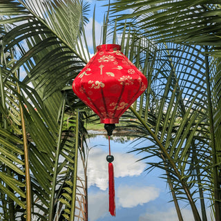 Lozenge shaped Vietnamese Hoi an Lantern on the Thu Bon River with reflections of clouds in the river with palm trees.