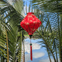 Lozenge shaped Vietnamese Hoi an Lantern on the Thu Bon River with reflections of clouds in the river with palm trees.