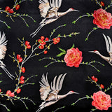 up close picture of polyester silk fabric featuring a print of herons in flight surrounded by pink flowers on black background