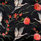 A close up of polyester silk fabric featuring a print of herons in flight surrounded by pink flowers on black background.