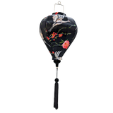 balloon shaped Vietnamese lantern made in Hoi An with a print of heron birds in flight surrounded by pink flowers on striking black background