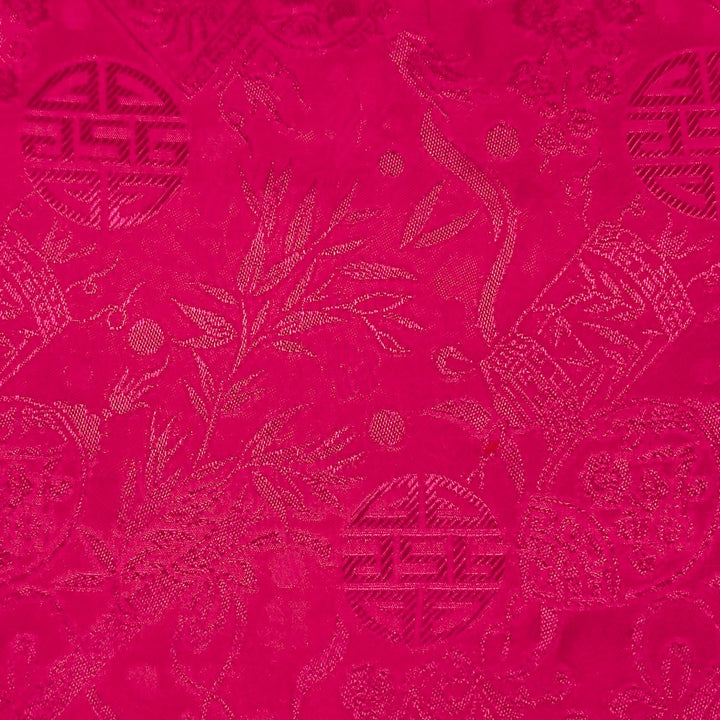 Close up of jacquard silk fabric with intricate patterns of bamboo, lanterns and symbols in hot pink colour.