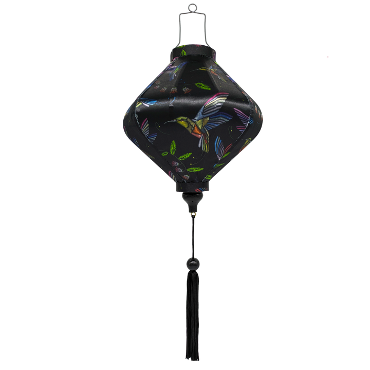 Lozenge shaped Vietnamese Hoi An Lantern with print of colourful cross stitched hummingbirds in flight amongst blue bell flowers and bright green leaves on black background. 