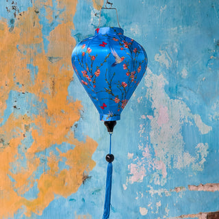 Balloon shape Vietnamese silk lantern with hummingbirds on blue against an aging wall in Old Town, Hoi An.