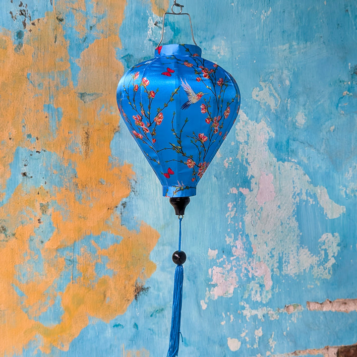Balloon shape Vietnamese silk lantern with hummingbirds on blue against an aging wall in Old Town, Hoi An.