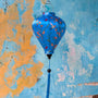 Balloon shape Vietnamese silk lantern with hummingbirds on blue against an aging wall in Old Town, Hoi An.