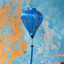 Balloon shape Vietnamese silk lantern with hummingbirds on blue against an aging wall in Old Town, Hoi An.