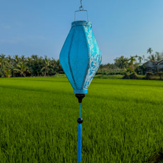 Blue and Silver Jacquard silk lantern hanging against a green field and blue sky