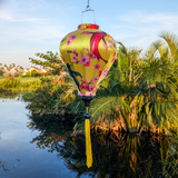 Balloon shaped Vietnamese lantern with yellow tassel with orange and black koi fish among cherry blossoms on a bold yellow silk.