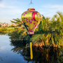 Balloon shaped Vietnamese lantern with yellow tassel with orange and black koi fish among cherry blossoms on a bold yellow silk.