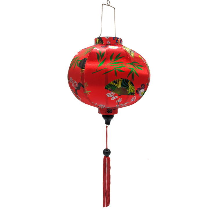 Round Vietnamese lantern with red tassel with black, yellow and green lanterns and multi colour fans surrounded by white cherry blossoms on a bold red background.