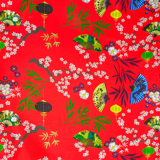 Up close polyester silk fabric with black, yellow and green lanterns and multi colour fans surrounded by white cherry blossoms on a bold red background.