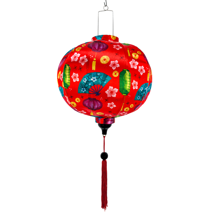 Round silk lantern featuring green lanterns, teal fans, gold coins and pink flowers on red lantern with matching red tassel.