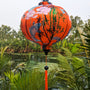 Round Vietnamese lantern hanging outdoors with a river in the background.