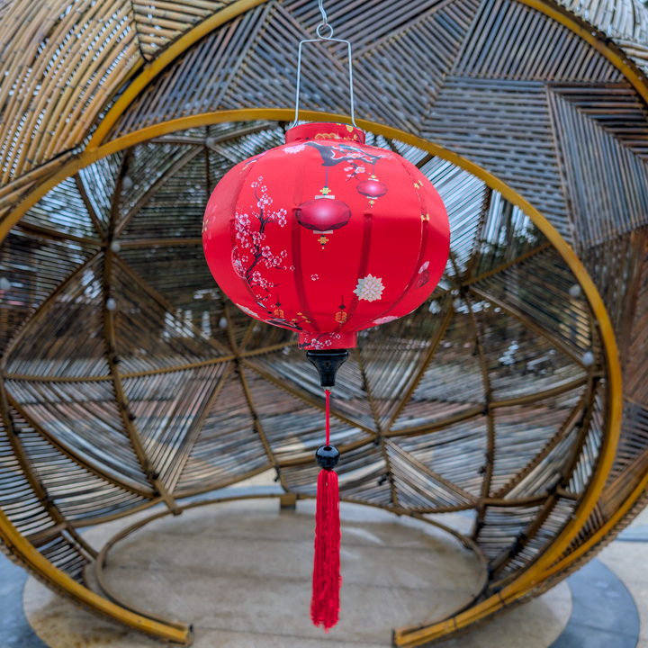 Red round lantern with tassel hanging against a woven basket background