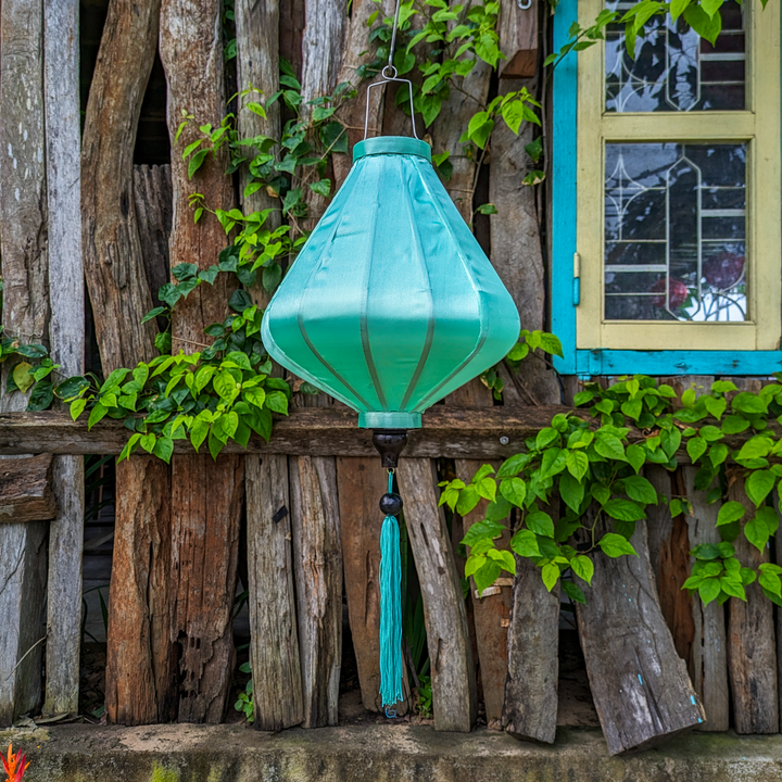 Mint Green Teardrop shape lantern hanging on a rustic wooden wall with greenery