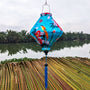 Lozenge shaped lantern outdoors with blue tassel and large orange birds on blue super silk fabric.