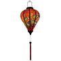 Glowing Balloon shaped lantern with red tassel adorned with intricate prints of dragons, peacocks, and butterflies against a striking red background.