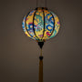Glowing round silk lantern with dragon and peacock design on a yellow background