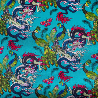 Close up of polyester silk fabric with flamboyant peacocks, butterflies and dragons against a striking blue background.