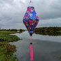 Tube shaped Vietnamese lantern hanging in front of a river and palm trees in the background.