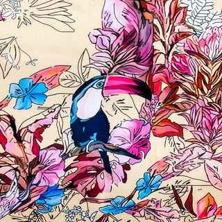 Polyester silk fabric with a print of large toucans sitting in a lush garden on a cream background. 