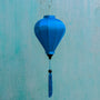 Balloon shaped blue plain silk Vietnamese lantern in front of an aging blue wall in Old Town, Hoi An.