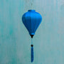 Balloon shaped blue plain silk Vietnamese lantern in front of an aging blue wall in Old Town, Hoi An.