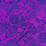 Close up of jacquard silk fabric with intricate patterns of bamboo, lanterns and symbols in blue against striking purple background.