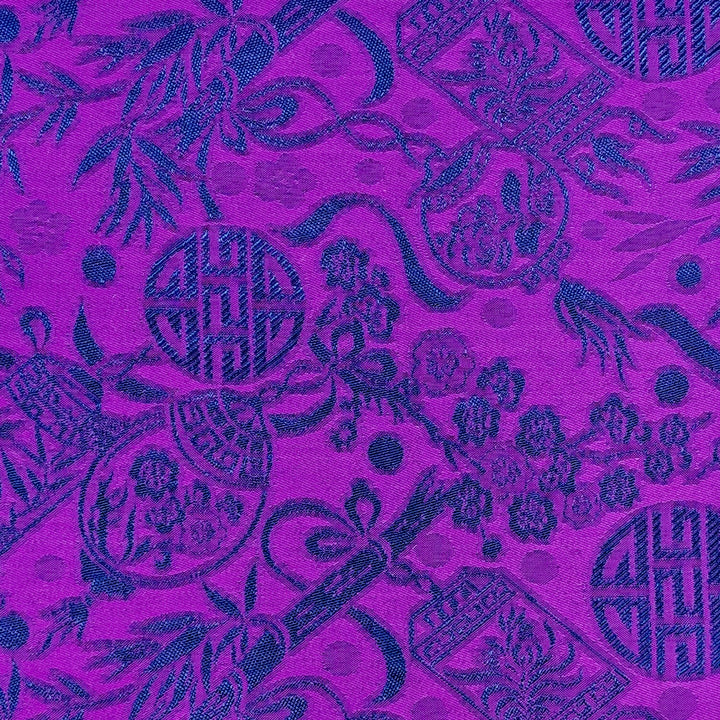 Close up of jacquard silk fabric with intricate patterns of bamboo, lanterns and symbols in blue against striking purple background.