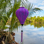 Balloon shaped Jacquard silk Purple lantern with matching purple tassel hanging by a river in Hoi An with palm trees in the background