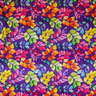 A close up of polyester silk fabric with green, pink, purple, orange, yellow leaves set against a rich purple background. 