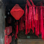 Red silk lantern surrounded by red ribbons and paper lanterns with flowers in Old Town, Hoi An.