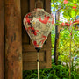 Balloon shaped lantern with red koi fish design hanging against a wooden background with greenery.