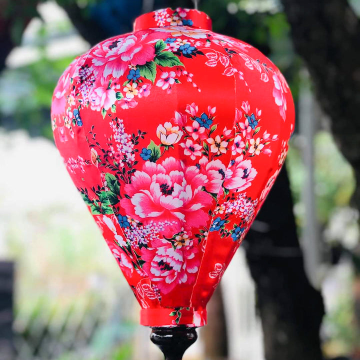 Close up of a balloon shape lantern featuring a print of pink roses against striking red silk.