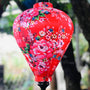 Close up of a balloon shape lantern featuring a print of pink roses against striking red silk.