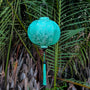 Sea green / turquoise Vietnamese Jacquard silk lantern with matching tassel hanging among palm trees