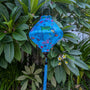 Lozenge shaped lantern with a print of different sea creatures hanging in a garden.