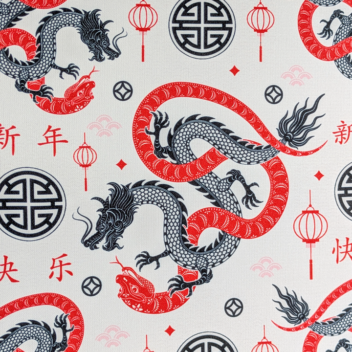 A close up of polyester silk fabric featuring entwined red serpentines and black dragons surrounded by lanterns, symbols, and swirls against white background.