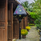 Teardrop shaped Vietnamese Hoi An lantern with a print of flying swallows with striking red and blue wings set against a bold black backdrop adorned with diamonds and yellow daisy flowers in a garden with a row of brown doors and beautiful flowers in the background. Perfect decor for the garden!