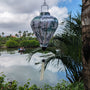 Balloon shaped Vietnamese lantern with a print of pagodas and temples above misty hilltops with large bamboo trees in the wild with people traveling up the river in a coconut basket.