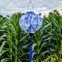 A round shape Vietnamese lantern with a blue print of bamboo and temples against white silk hanging in front of a corn field in Hoi An, Vietnam.