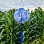 A round shape Vietnamese lantern with a blue print of bamboo and temples against white silk hanging in front of a corn field in Hoi An, Vietnam.