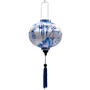 A round Vietnamese silk lantern from Vietnam features a blue print of temples and pagodas high above hilltops with large bamboo trees floating against white background. 