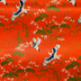 Vibrant orange polyester silk fabric adorned with elegant cranes and lush tree patterns, used to handcraft lanterns in Hoi An.
